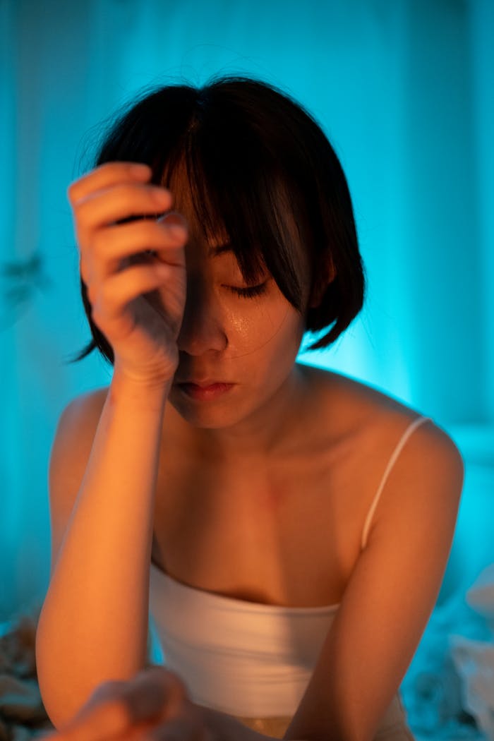 Close-up of a woman with hand on face expressing deep emotion and stress.